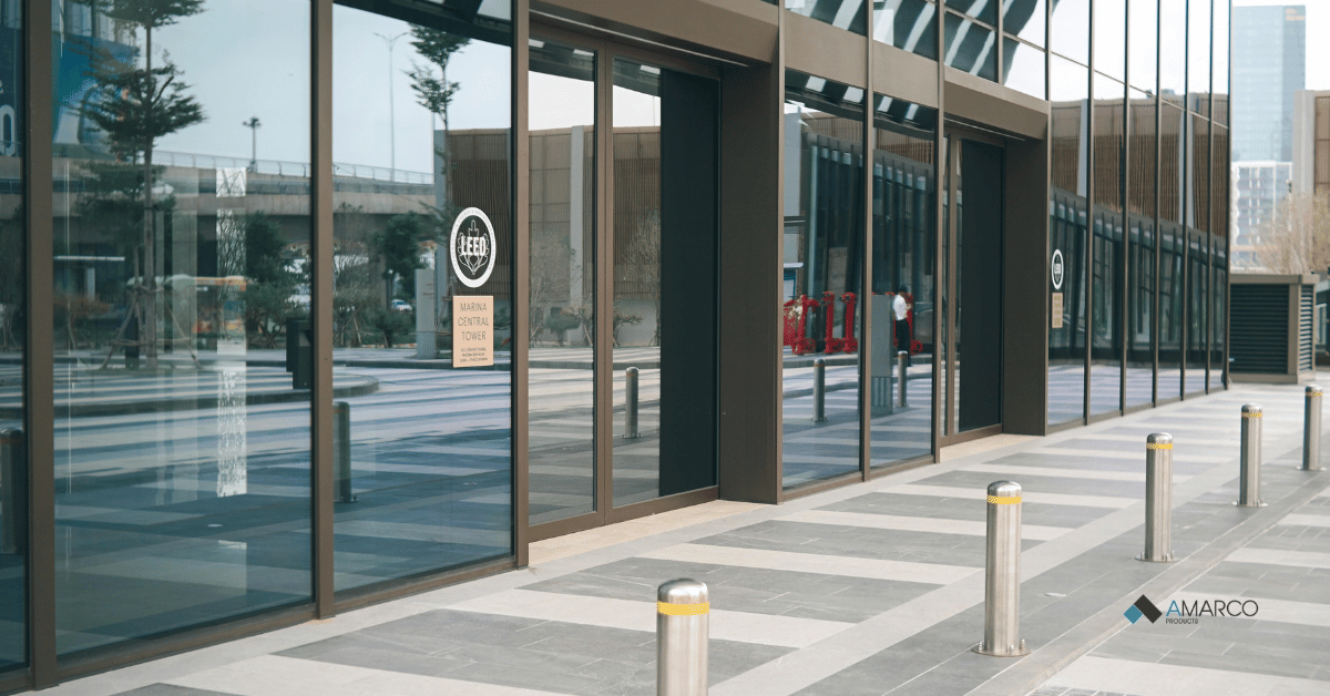Modern glass building entrance with bollards and durable commercial entrance matting.
