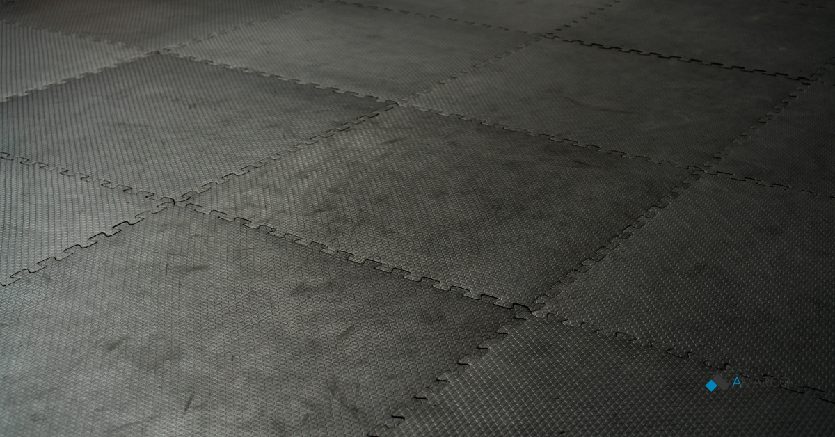 Interlocking durable gym floor mats showcasing a comparison of re-vulcanized vs. urethane-bonded rubber texture.